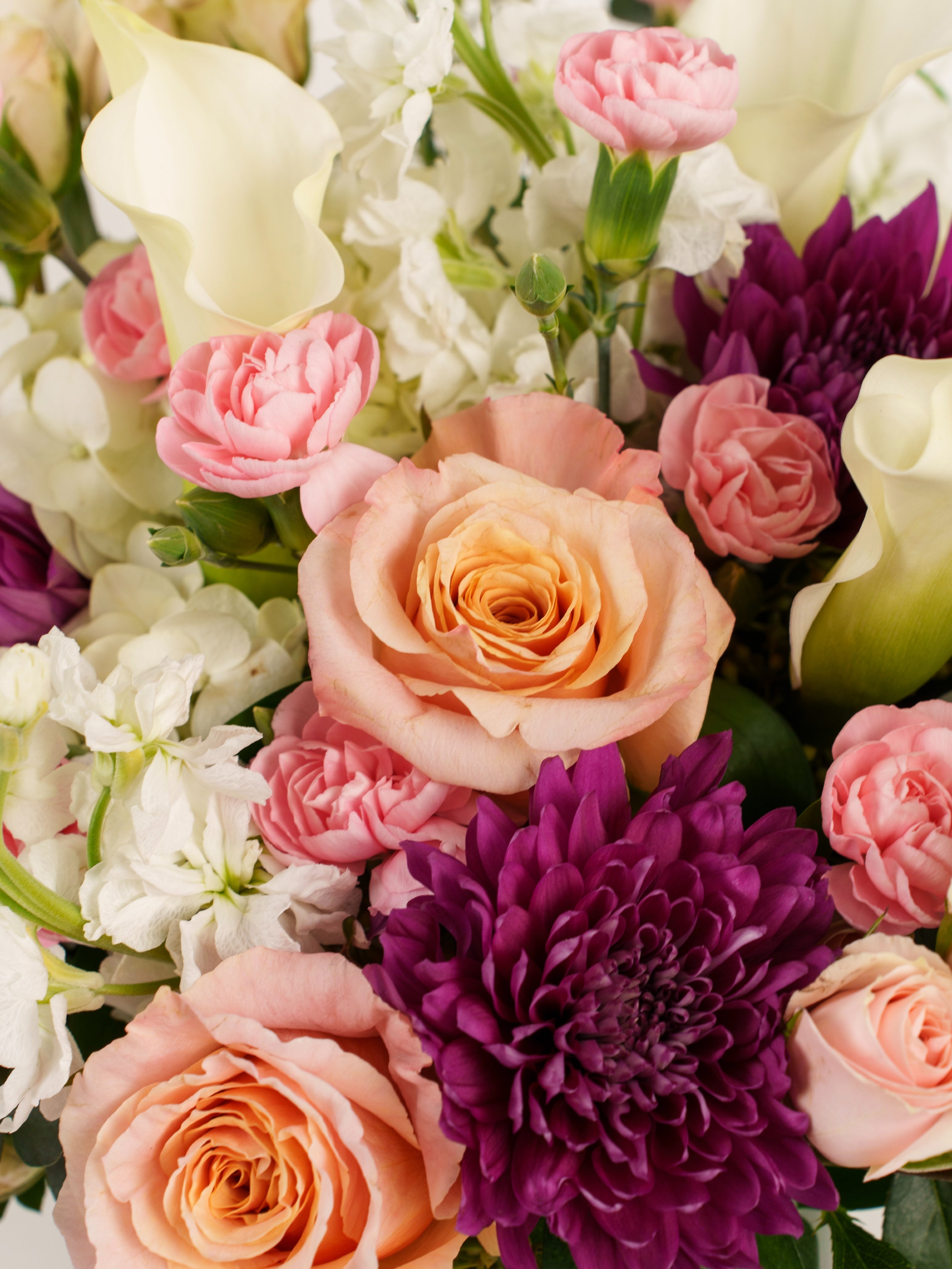 Secret Garden bouquet with roses, stock & calli lilies in a vase.